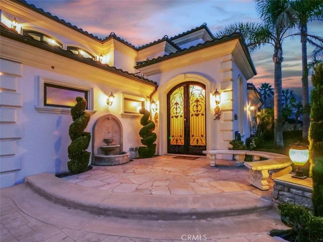 exterior entry at dusk featuring a patio area