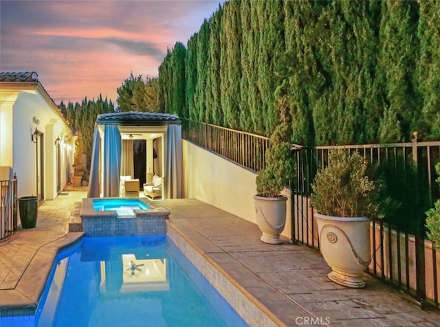 pool at dusk with an in ground hot tub