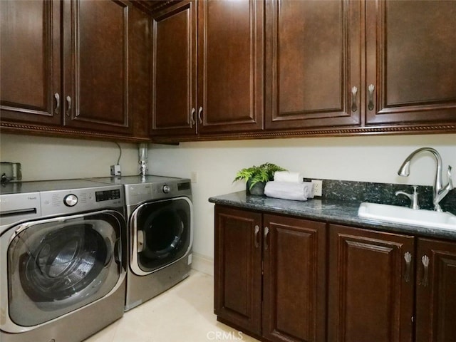 clothes washing area with sink, washing machine and dryer, and cabinets