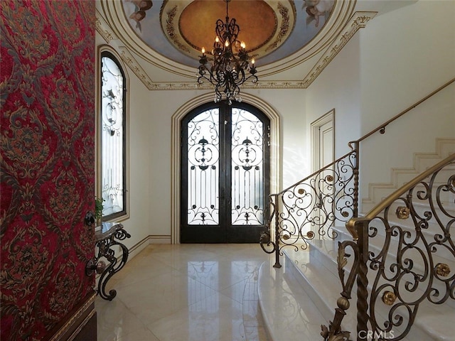 foyer with a notable chandelier, a tray ceiling, and french doors