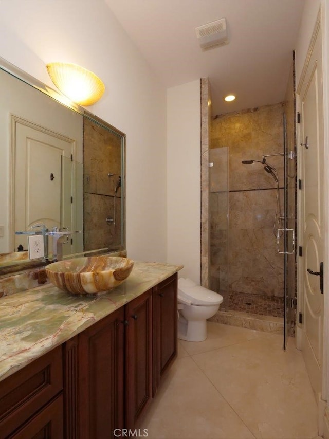 bathroom with vanity, tile patterned flooring, toilet, and a tile shower