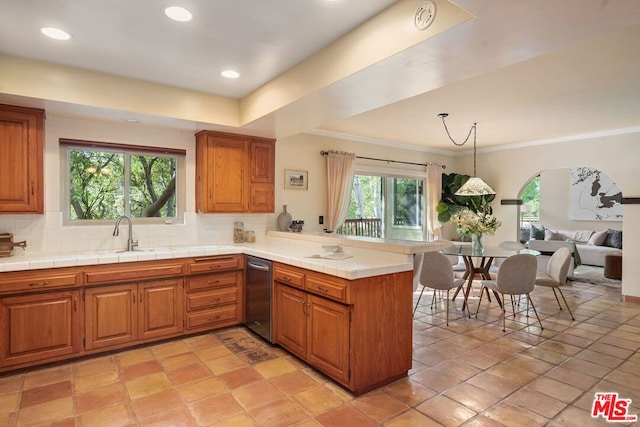 kitchen featuring decorative light fixtures, tasteful backsplash, tile counters, kitchen peninsula, and crown molding