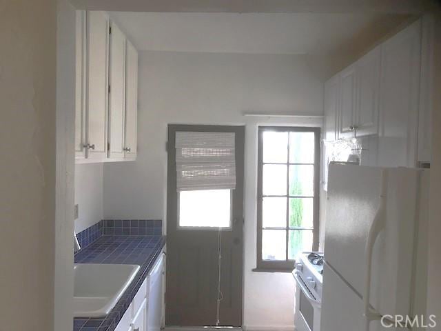 kitchen featuring white cabinetry, sink, tile counters, and white appliances