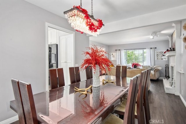 dining space featuring a fireplace, dark hardwood / wood-style floors, and a chandelier