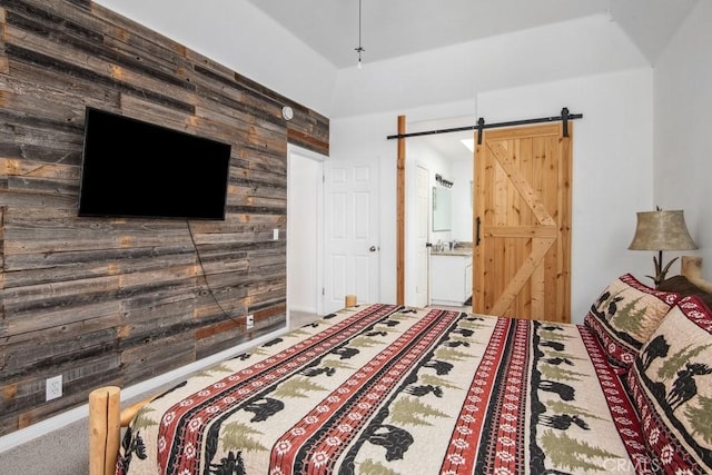 unfurnished bedroom featuring ensuite bathroom, a barn door, carpet floors, and wood walls