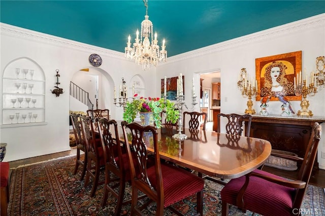 dining area featuring dark hardwood / wood-style flooring, a notable chandelier, built in features, and ornamental molding