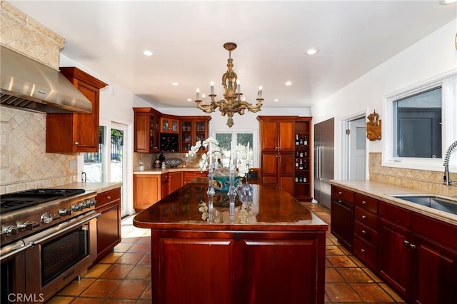 kitchen with high end appliances, a center island, sink, and range hood