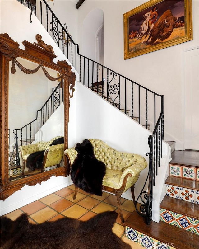 stairway featuring tile patterned flooring and a towering ceiling