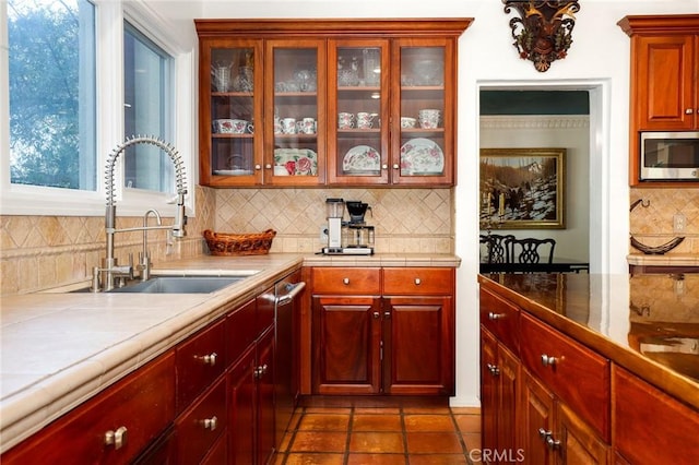 kitchen featuring stainless steel appliances, sink, decorative backsplash, and dark tile patterned floors