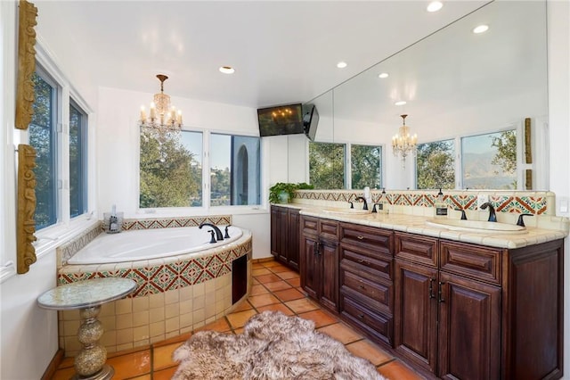 bathroom with an inviting chandelier, backsplash, tile patterned flooring, a relaxing tiled tub, and vanity