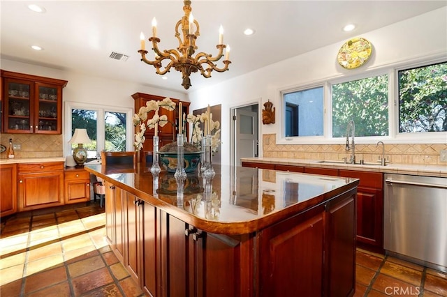 kitchen featuring sink, decorative light fixtures, dishwasher, a kitchen island, and backsplash