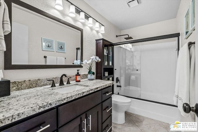 full bathroom featuring bath / shower combo with glass door, vanity, a textured ceiling, tile patterned floors, and toilet