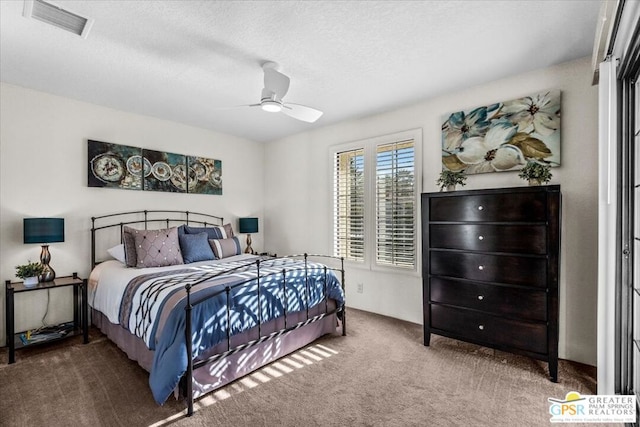 carpeted bedroom with ceiling fan and a textured ceiling