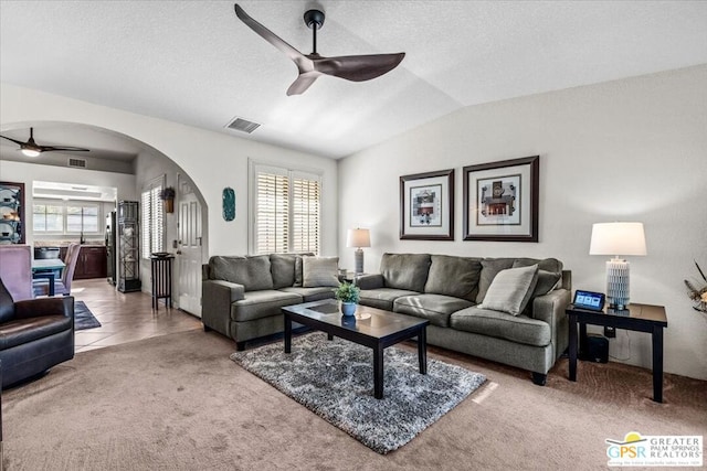 carpeted living room featuring vaulted ceiling, a textured ceiling, and ceiling fan