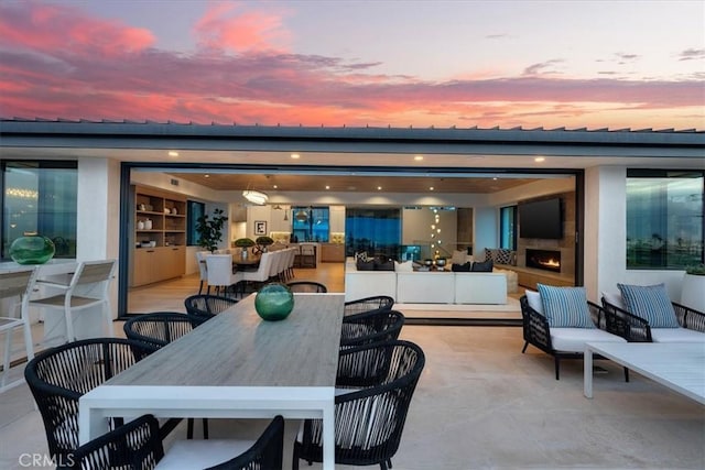 patio terrace at dusk featuring an outdoor living space with a fireplace