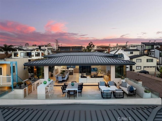 back house at dusk featuring an outdoor bar and exterior kitchen