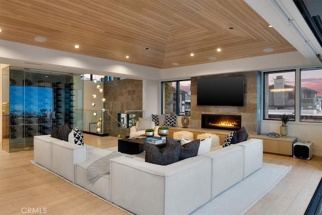 living room featuring wood ceiling, light hardwood / wood-style floors, and a large fireplace