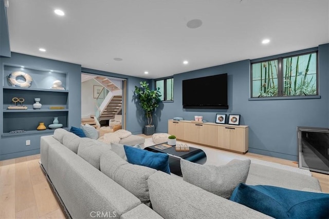 living room featuring built in features and light hardwood / wood-style floors