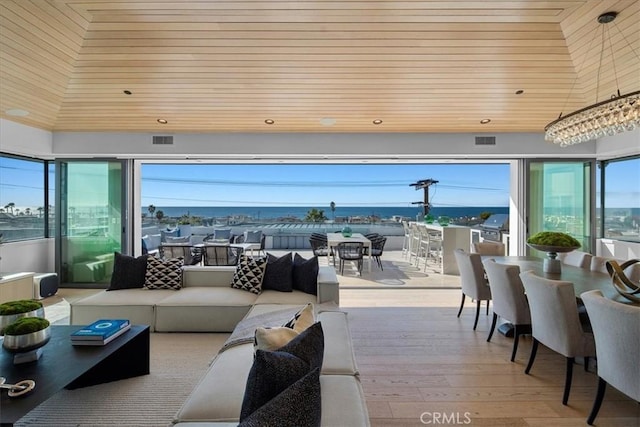 interior space with a bar, an outdoor living space, grilling area, and a water view