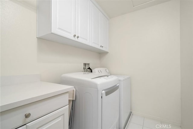 laundry room featuring cabinets, light tile patterned floors, and washer and clothes dryer