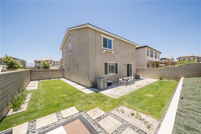 back of house featuring central AC unit, a patio area, and a lawn