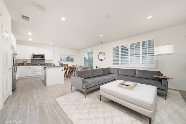 living room with sink and light wood-type flooring