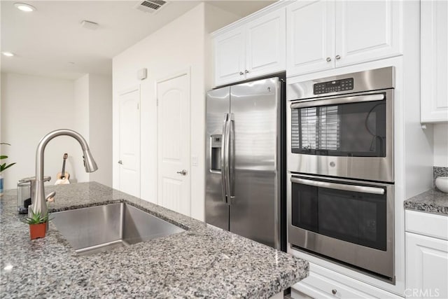 kitchen with light stone counters, sink, stainless steel appliances, and white cabinets