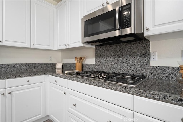 kitchen featuring white cabinetry, tasteful backsplash, stainless steel appliances, and dark stone counters