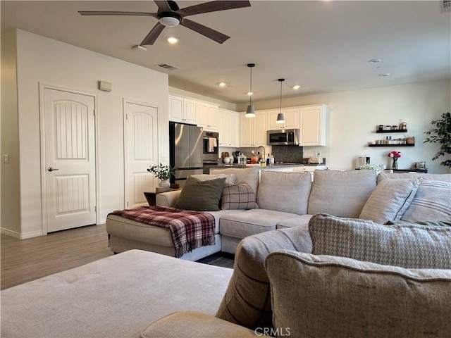 living room featuring ceiling fan and light wood-type flooring