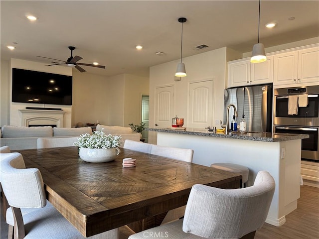 dining space with ceiling fan, dark hardwood / wood-style floors, and sink