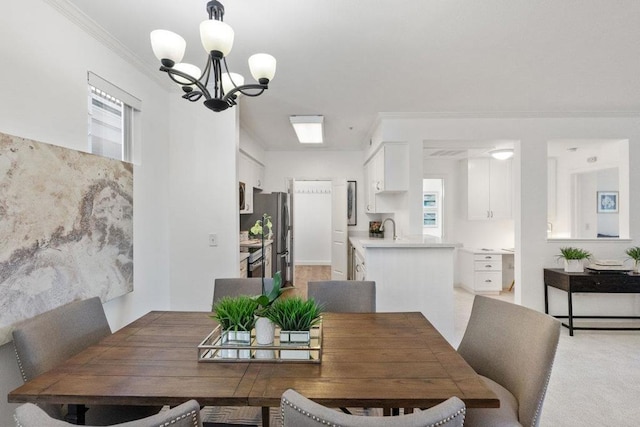 dining area featuring crown molding, carpet floors, sink, and an inviting chandelier