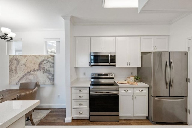 kitchen featuring ornamental molding, appliances with stainless steel finishes, white cabinets, and a chandelier