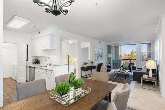 dining space featuring ornamental molding, light hardwood / wood-style floors, sink, and a notable chandelier