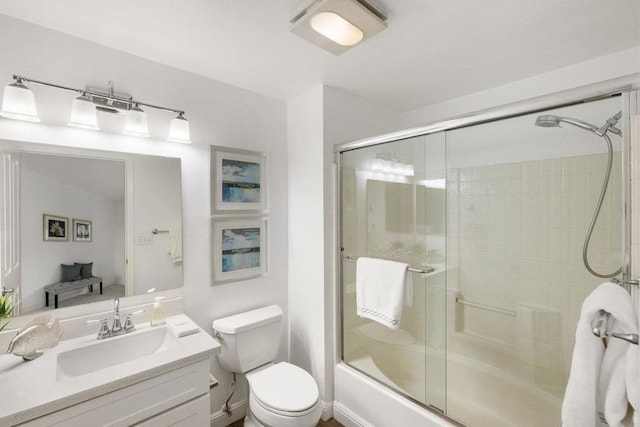 full bathroom with enclosed tub / shower combo, vanity, and toilet