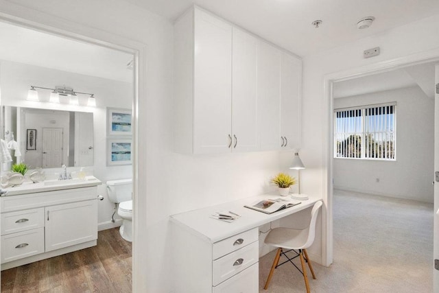 office space featuring sink, built in desk, and dark hardwood / wood-style floors