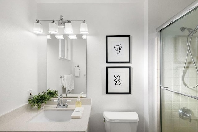 bathroom featuring an enclosed shower, vanity, and toilet