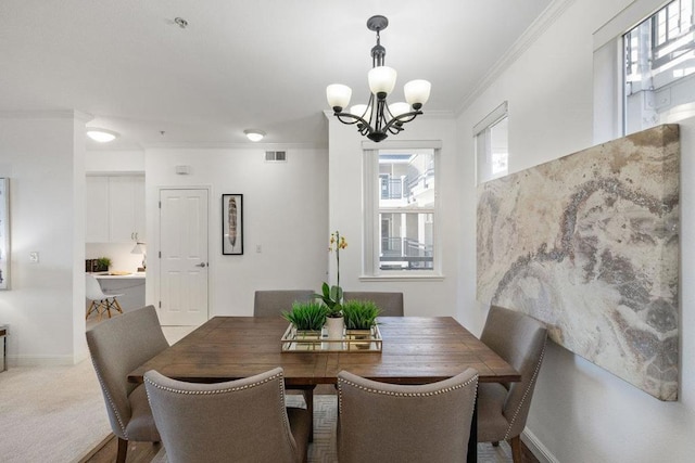 dining space with ornamental molding, light carpet, and a chandelier