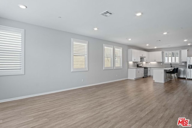 unfurnished living room with sink and light hardwood / wood-style flooring