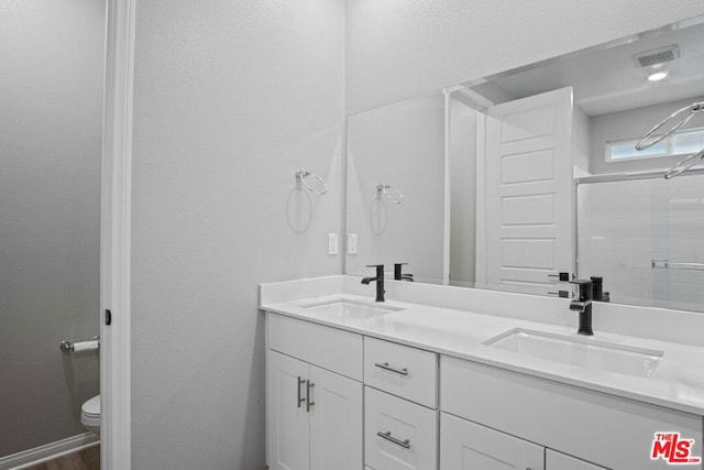 bathroom featuring vanity, a shower with shower door, and toilet