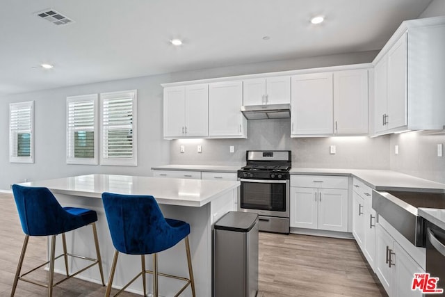 kitchen with appliances with stainless steel finishes, a center island, light hardwood / wood-style flooring, and white cabinets