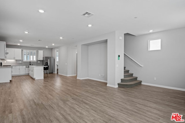 unfurnished living room with sink and light hardwood / wood-style flooring