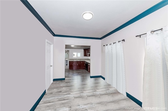 corridor with crown molding, sink, and light hardwood / wood-style flooring