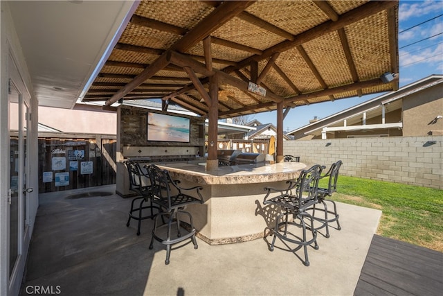 view of patio / terrace featuring an outdoor kitchen, fence, outdoor dry bar, and a gazebo