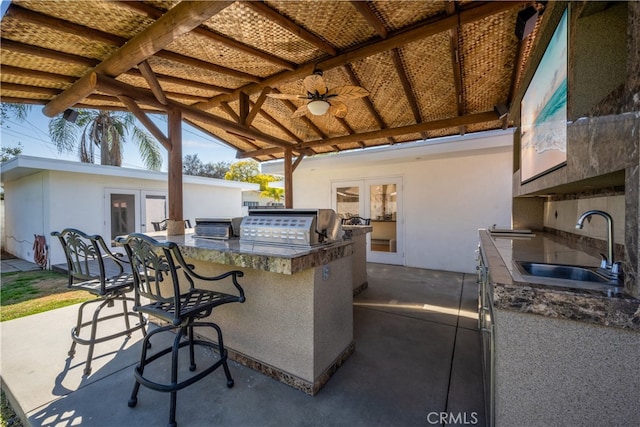 view of patio with ceiling fan, an outdoor kitchen, outdoor wet bar, area for grilling, and a sink