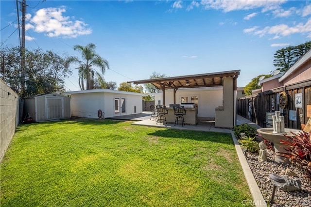 rear view of house with a storage shed, a lawn, a patio, a fenced backyard, and an outbuilding