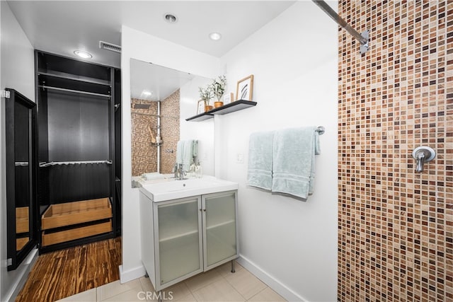 full bathroom featuring baseboards, visible vents, tile patterned floors, a tile shower, and vanity