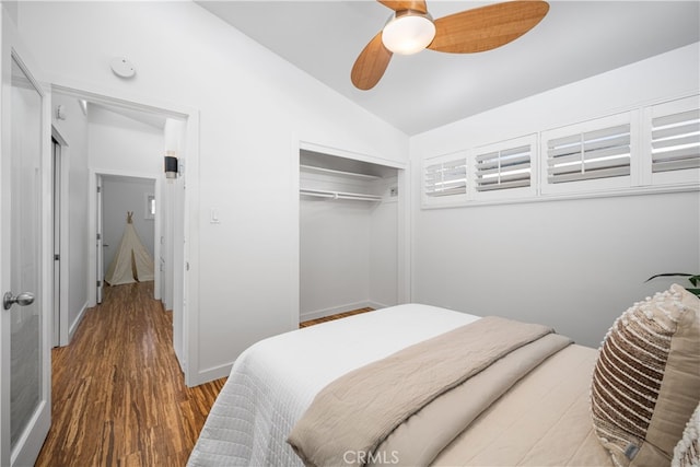 bedroom with wood finished floors, a ceiling fan, baseboards, vaulted ceiling, and a closet