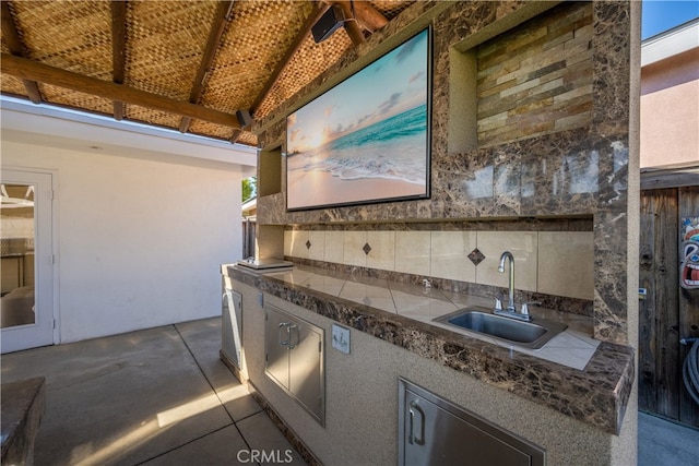 kitchen featuring dark countertops, decorative backsplash, and a sink