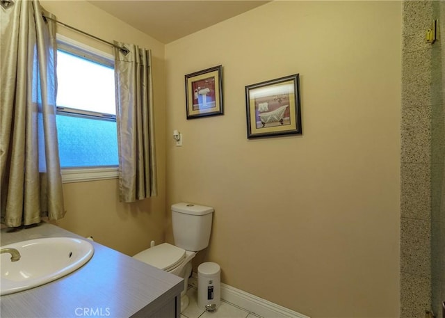 bathroom featuring toilet, tile patterned flooring, baseboards, and vanity