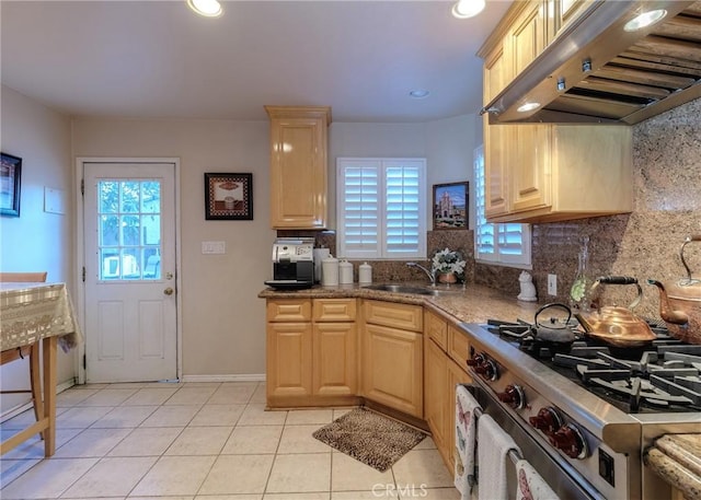 kitchen featuring light brown cabinetry, stainless steel range with gas cooktop, extractor fan, and a sink